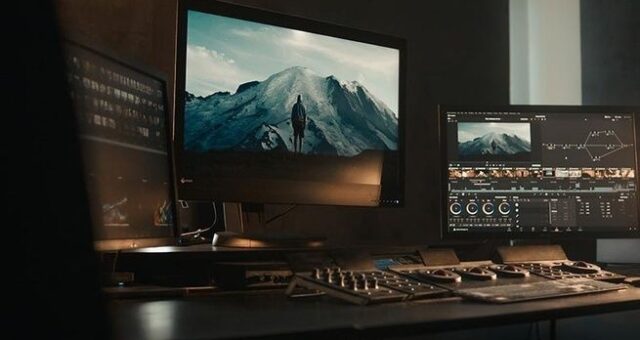 Färgkorrigeringsstudio med monitorer och bergsbild i färggradering